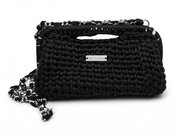 A black woven shoulder bag with a silver-tone metal brand plaque and chain strap, photographed on a clean white background.