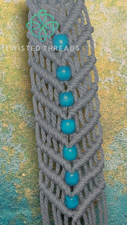 White V-shaped macrame plant hanger with beads by Twisted Threads Au, perfect for displaying potted plants indoors.