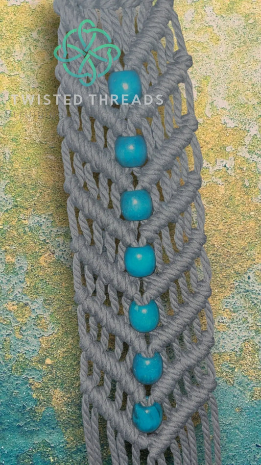 White macrame plant hanger with V design and beads by Twisted Threads Au, perfect for displaying potted plants.